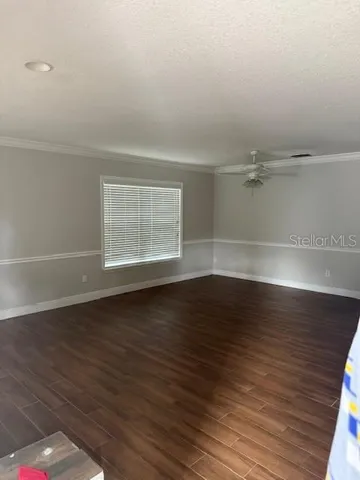 a view of an empty room with wooden floor and a window
