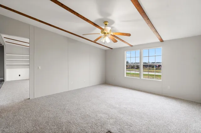 a view of an empty room with window and chandelier fan