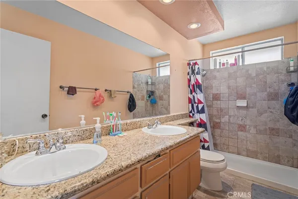 a bathroom with a granite countertop sink a toilet and a mirror