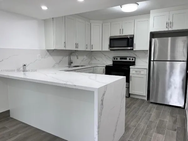 a kitchen with a sink a microwave a refrigerator and cabinets