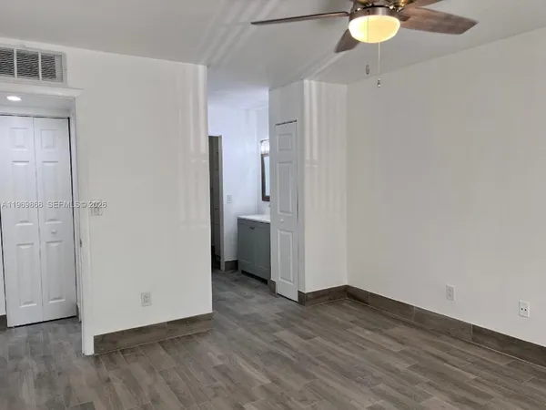 an empty room with wooden floor and bathroom view