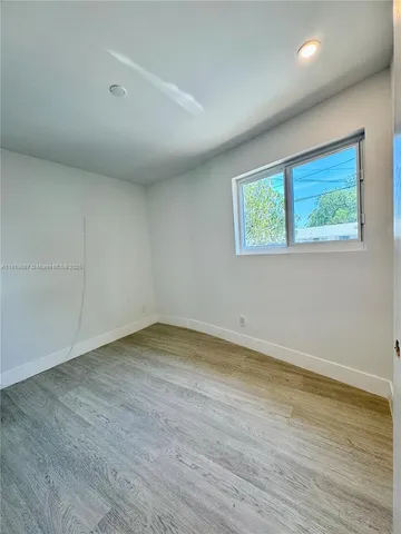 an empty room with wooden floor and window