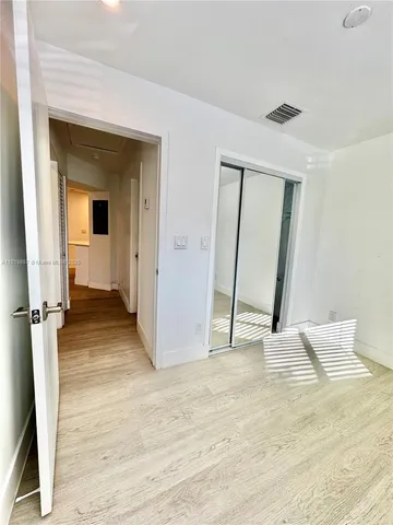 an empty room with wooden floor and a bathroom