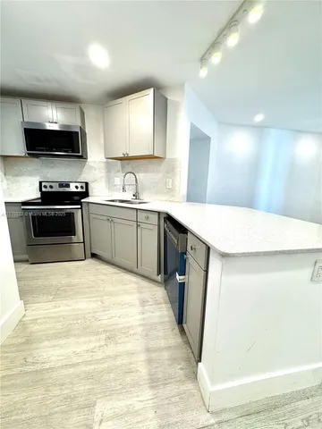 a large kitchen with stainless steel appliances lots of counter space and wooden floor