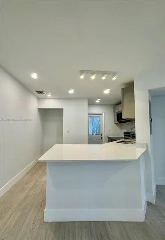 a large white kitchen with kitchen island a sink a stove a refrigerator and a stove