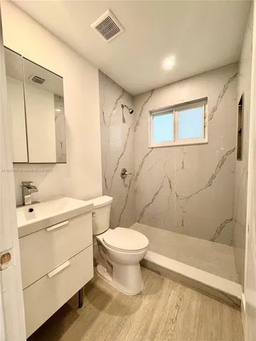 a bathroom with a sink toilet vanity and shower