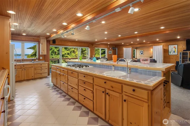 a large kitchen with kitchen island a large counter top and stainless steel appliances