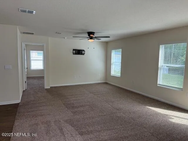 an empty room with windows and fan