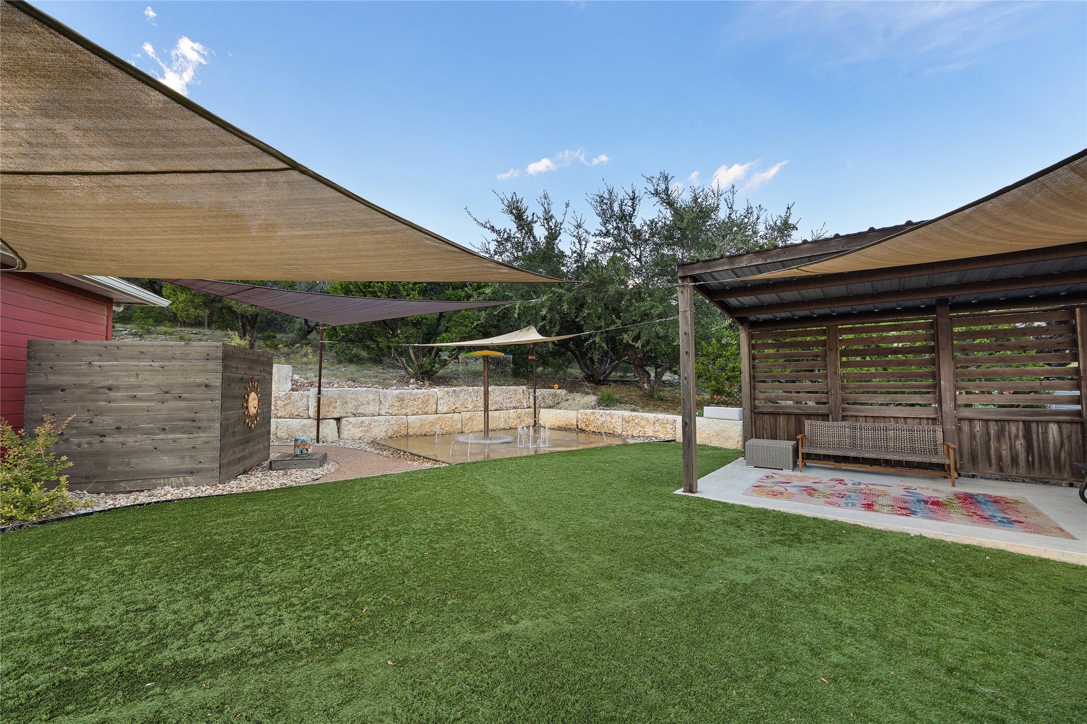 1017 Westland Ridge Road Dripping Springs, TX 78620 - Photo 33 of 40 A spacious lawn area includes a covered pavilion alongside stone retaining walls.