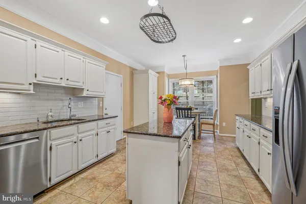 a kitchen with granite countertop kitchen island stainless steel appliances a stove refrigerator sink and cabinets
