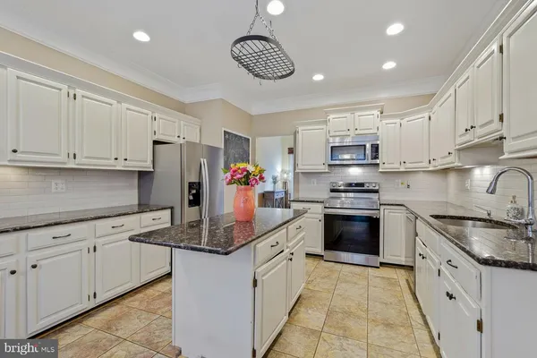 a kitchen with kitchen island granite countertop white cabinets white stainless steel appliances with a sink and dishwasher