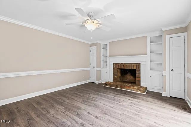 a view of a livingroom with a fireplace a ceiling fan and window