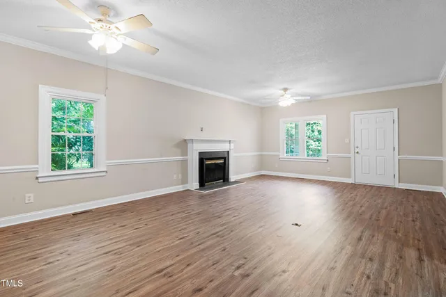 a view of an empty room with wooden floor fireplace and a window