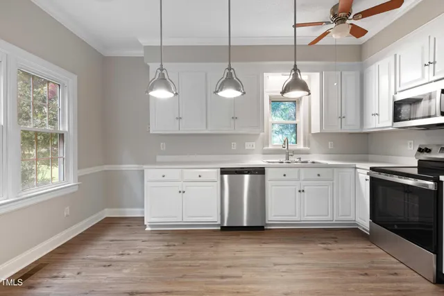 a kitchen with stainless steel appliances granite countertop a sink a stove a refrigerator and white cabinets