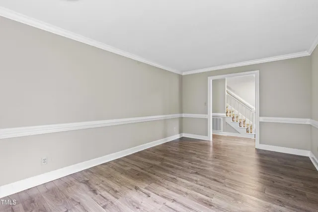 a view of an empty room with wooden floor fireplace and a window