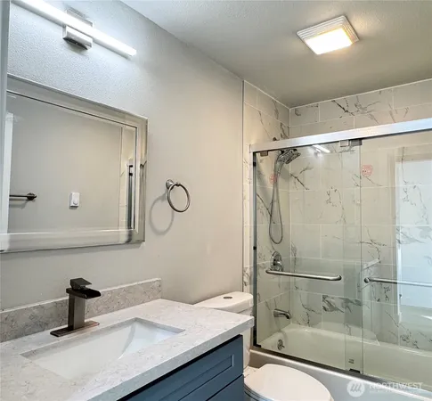 a bathroom with a granite countertop sink a toilet and shower