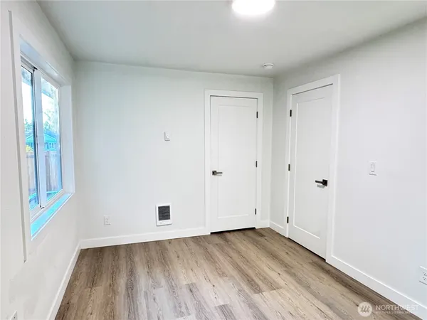 a view of an empty room with wooden floor and a window