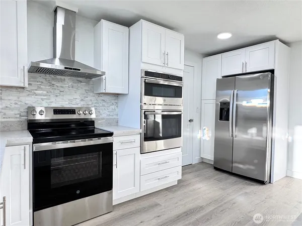 a kitchen with cabinets stainless steel appliances and wooden floor