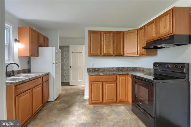 a kitchen with stainless steel appliances granite countertop a stove top oven a sink dishwasher and a refrigerator with wooden cabinets