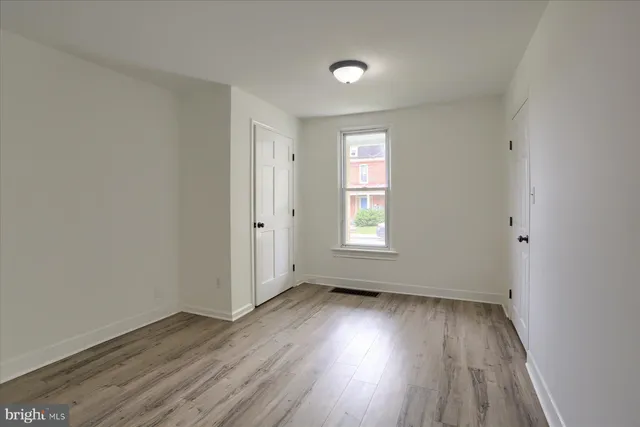 an empty room with wooden floor and windows