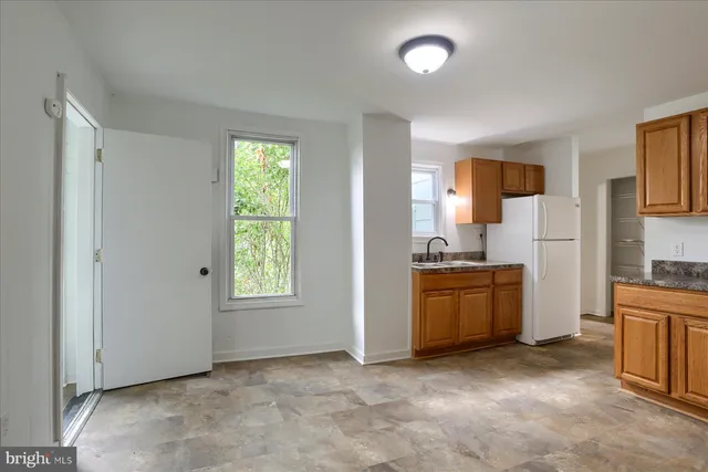 a view of a kitchen and an entryway and an empty room with kitchen
