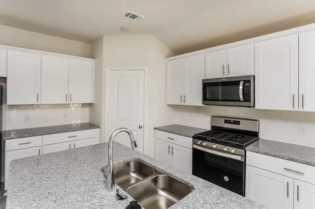 a kitchen with white cabinets and appliances