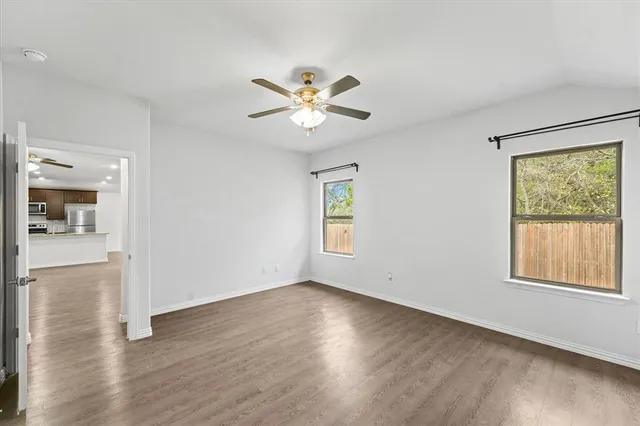 an empty room with wooden floor and windows