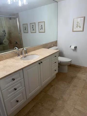 a bathroom with a granite countertop sink mirror and toilet