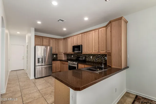 a kitchen with stainless steel appliances granite countertop a refrigerator a stove a sink and a microwave