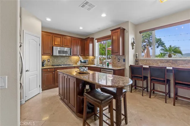 a kitchen with kitchen island granite countertop wooden cabinets and stainless steel appliances