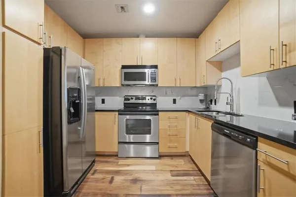 a kitchen with stainless steel appliances granite countertop a refrigerator stove and sink