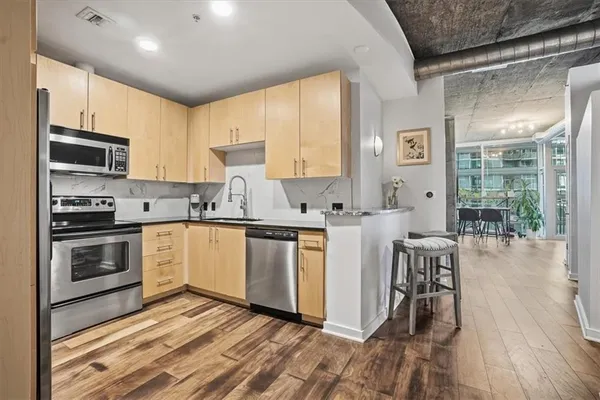 a kitchen with granite countertop a stove a sink a dining table and chairs