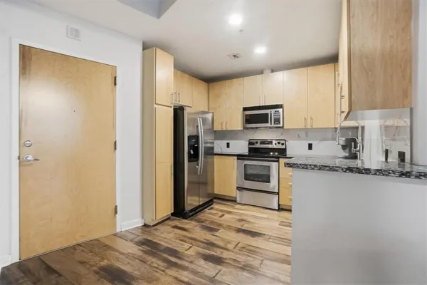 a kitchen with granite countertop a refrigerator and a stove top oven