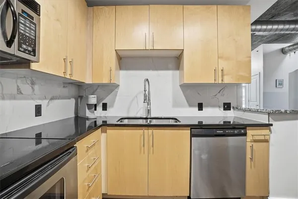 a kitchen with granite countertop a sink a stove and cabinets