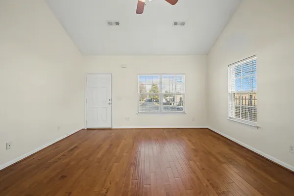 an empty room with wooden floor and windows
