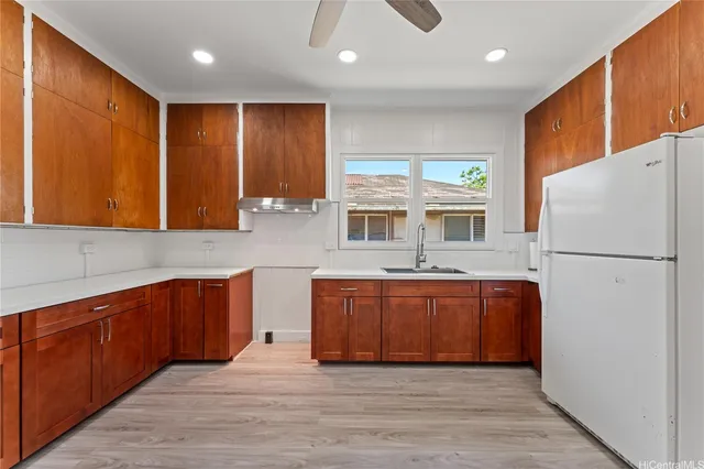 a kitchen with stainless steel appliances granite countertop a refrigerator a oven a sink with wooden cabinets and wooden floor