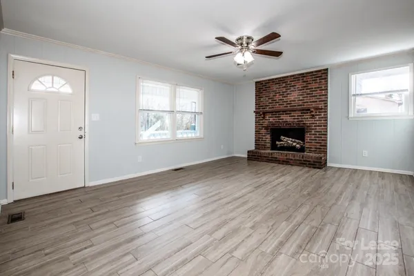 an empty room with wooden floor a fireplace and windows