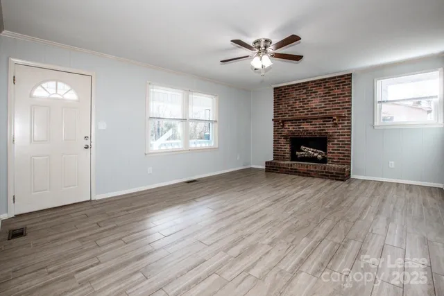 an empty room with wooden floor a fireplace and windows