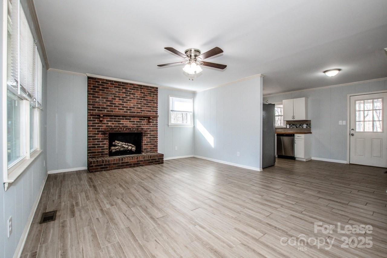1159 Camp Creek Road Iron Station, NC 28080 - Photo 13 of 48 an empty room with wooden floor a fireplace and windows