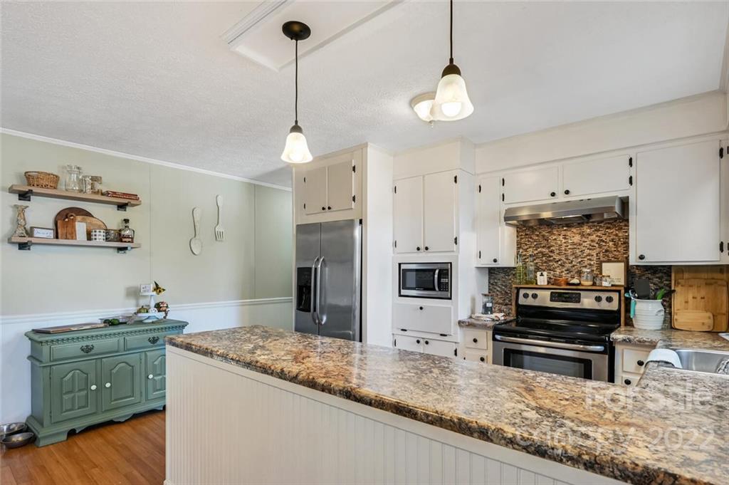 685 Kims Cove Road Canton, NC 28716 - Photo 15 of 43 a kitchen with stainless steel appliances granite countertop a stove a refrigerator and a sink with wooden floor