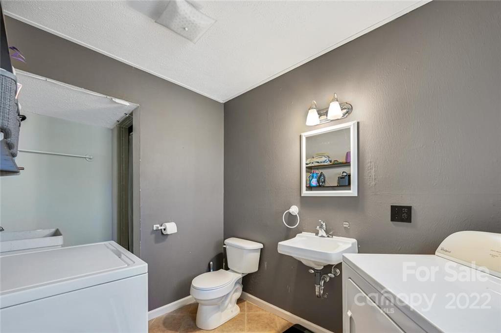685 Kims Cove Road Canton, NC 28716 - Photo 25 of 43 a bathroom with a granite countertop toilet a sink and a mirror