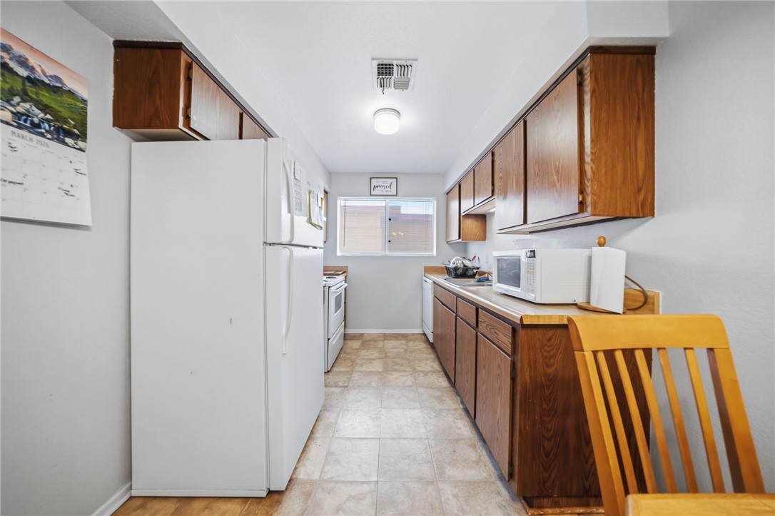 793 Baseline Road Bullhead City, AZ 86442 - Photo 17 of 49 Galley kitchen featuring wood cabinetry, laminate countertops, and tile flooring