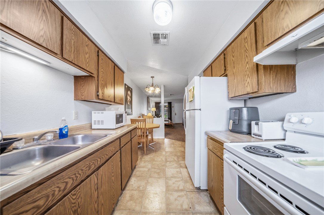 793 Baseline Road Bullhead City, AZ 86442 - Photo 21 of 49 Galley kitchen featuring wood-finish cabinetry, laminate countertops, and resilient vinyl flooring