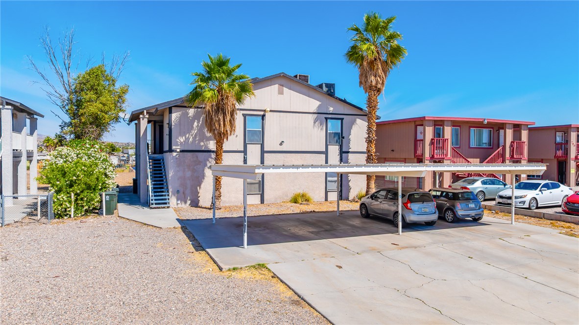 793 Baseline Road Bullhead City, AZ 86442 - Photo 42 of 49 Multi-unit building exterior featuring a carport, second-story access via exterior staircase, and mature palm trees