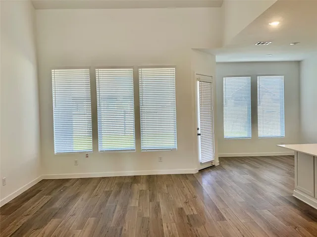 a large kitchen with a center island wooden floor stainless steel appliances and windows