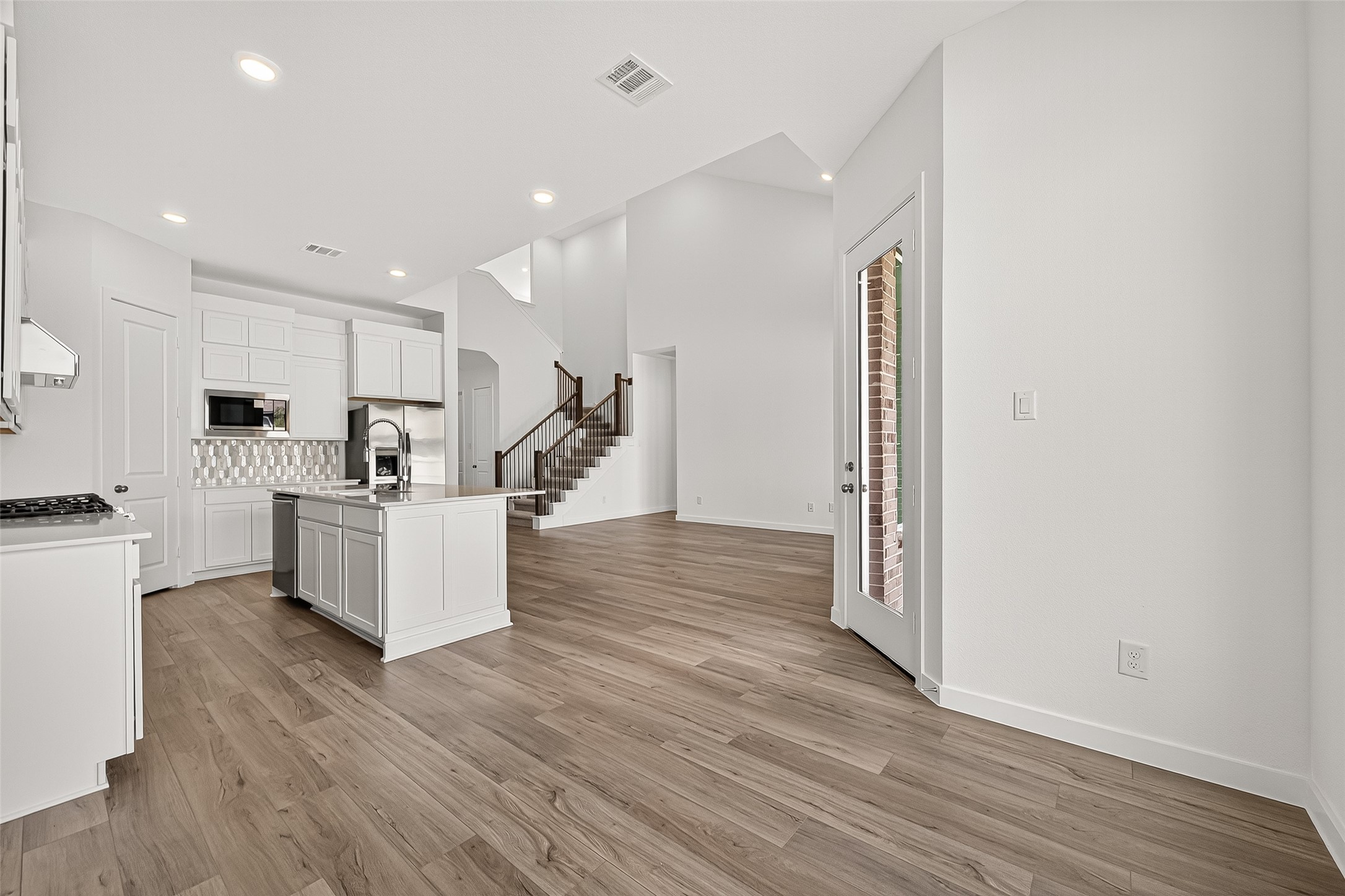 2419 Hazel Berry Street Manvel, TX 77578 - Photo 15 of 50 a large kitchen with a center island wooden floor stainless steel appliances and windows
