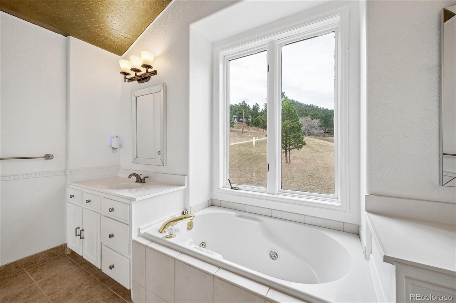 6320 Valley Lane Morrison, CO 80465 - Photo 13 of 28 a bathroom with a tub a sink and a window