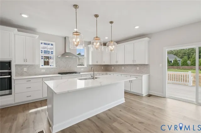 a view of a kitchen with stainless steel appliances granite countertop a stove a refrigerator a oven and a wooden floors