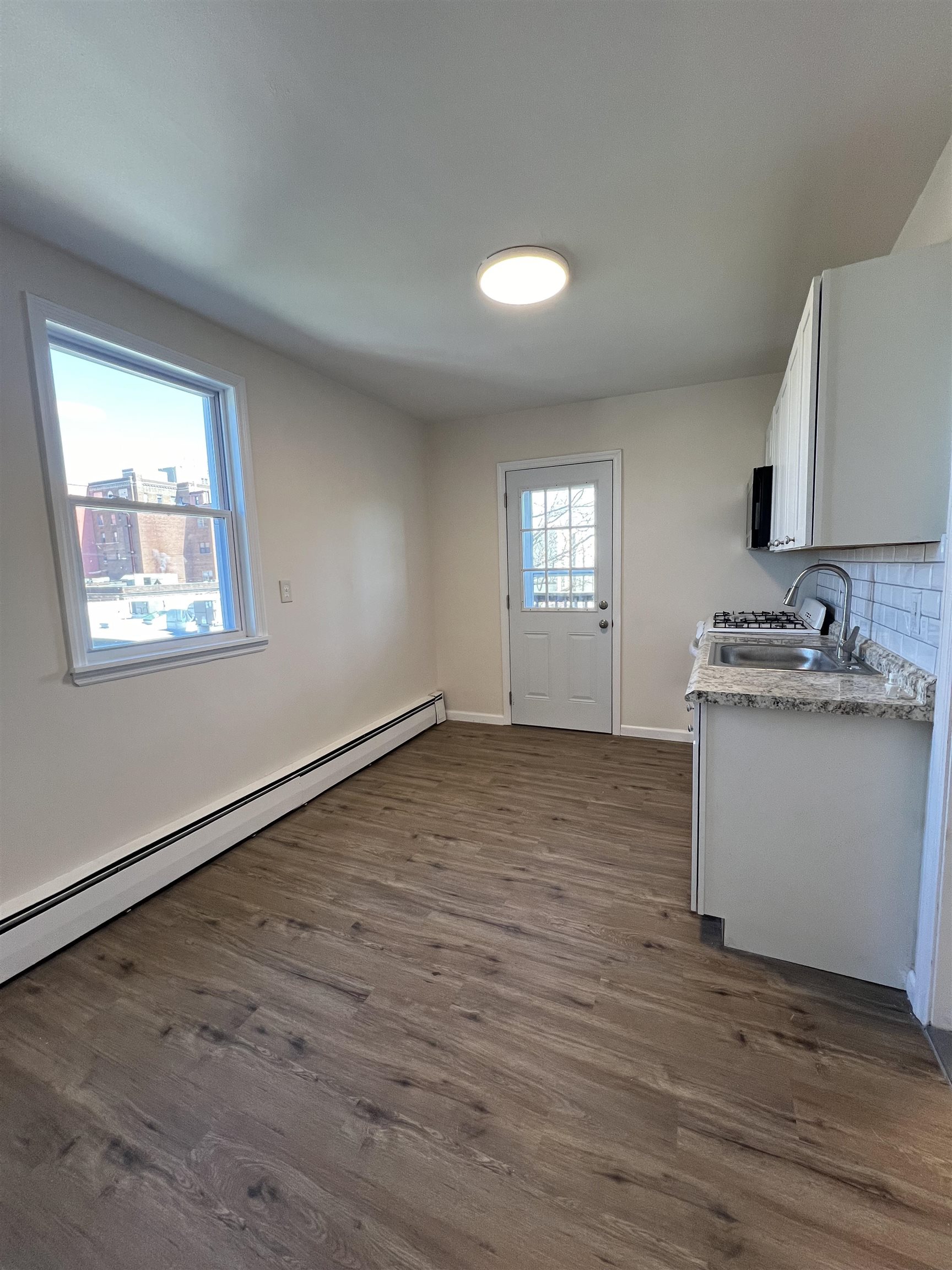 618 Broadway, Unit 5 Bayonne, NJ 07002 - Photo 4 of 9 a kitchen with granite countertop white cabinets and wooden floor