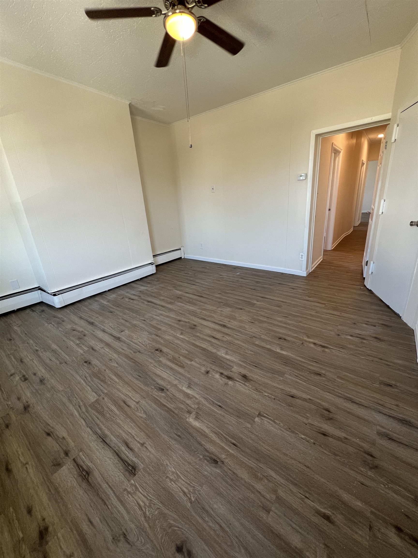 618 Broadway, Unit 5 Bayonne, NJ 07002 - Photo 6 of 9 an empty room with wooden floor fan and windows